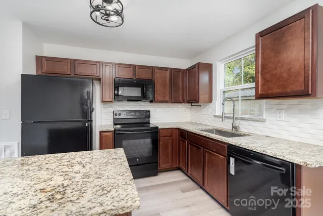a kitchen with stainless steel appliances granite countertop a sink stove microwave and refrigerator