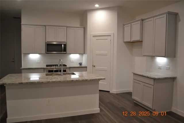 a kitchen with kitchen island granite countertop a sink a stove and refrigerator