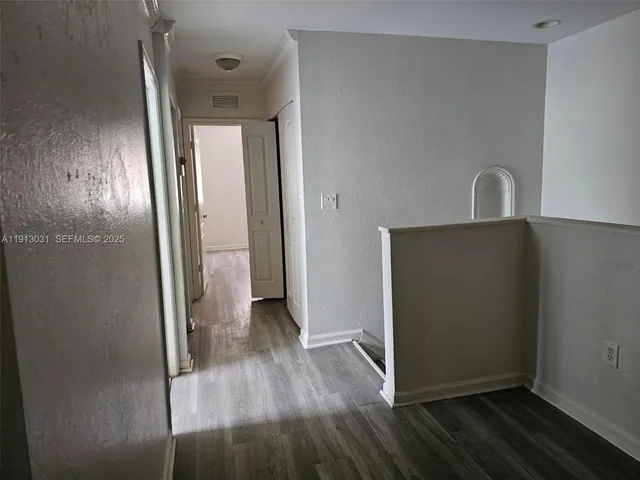 a view of a livingroom with wooden floor and a hallway