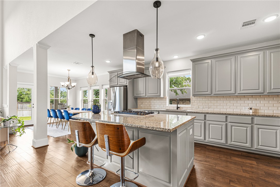 3632 Haskell Hollow Loop College Station, TX 77845 - Photo 8 of 42 a very nice looking kitchen with granite countertop a stove a sink a dining table and chairs with wooden floor