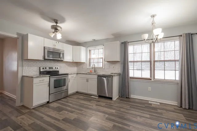 a kitchen with granite countertop a stove a sink dishwasher a refrigerator and a microwave oven with wooden floor