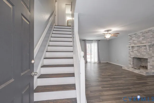 a view of an empty room with wooden floor and a fireplace