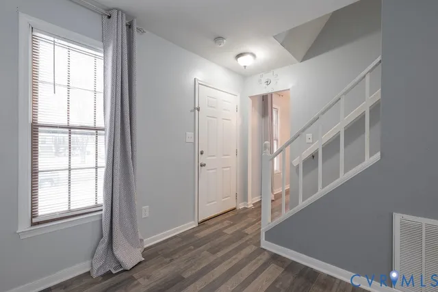 an empty room with wooden floor and windows