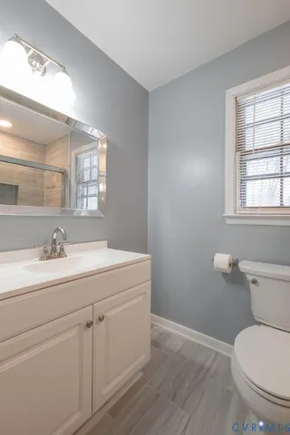 a bathroom with a toilet sink a window and mirror