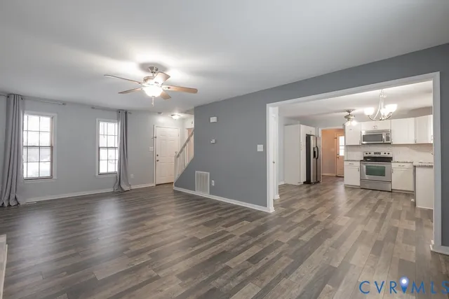 a view of an empty room with window and wooden floor