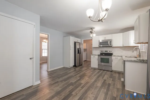 a kitchen with granite countertop a refrigerator cabinets and wooden floor