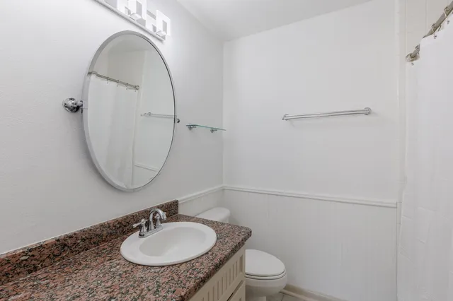 a bathroom with a sink a toilet and a mirror