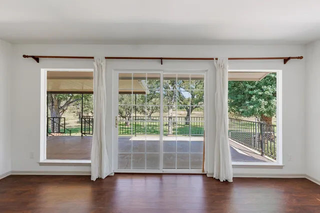 a view of empty room with wooden floor and floor to ceiling window