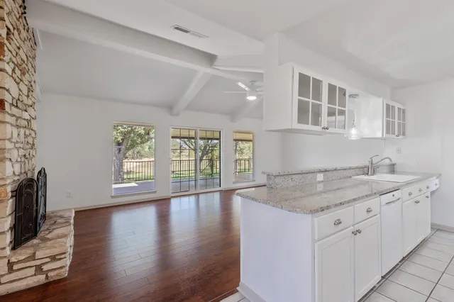a kitchen with a stove a sink and a granite counter tops with wooden floors