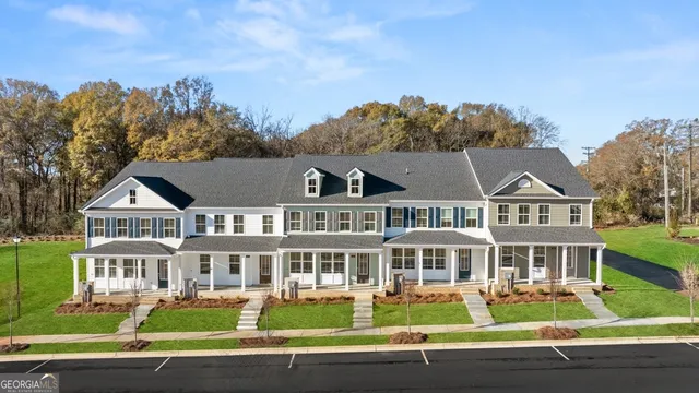 a front view of a house with a garden and trees in the background