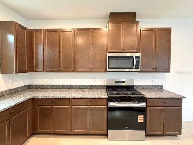a living room with couches and kitchen view of kitchen