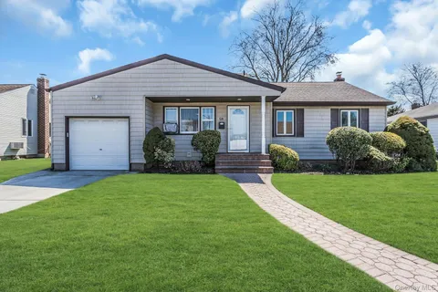 a front view of a house with a garden and plants