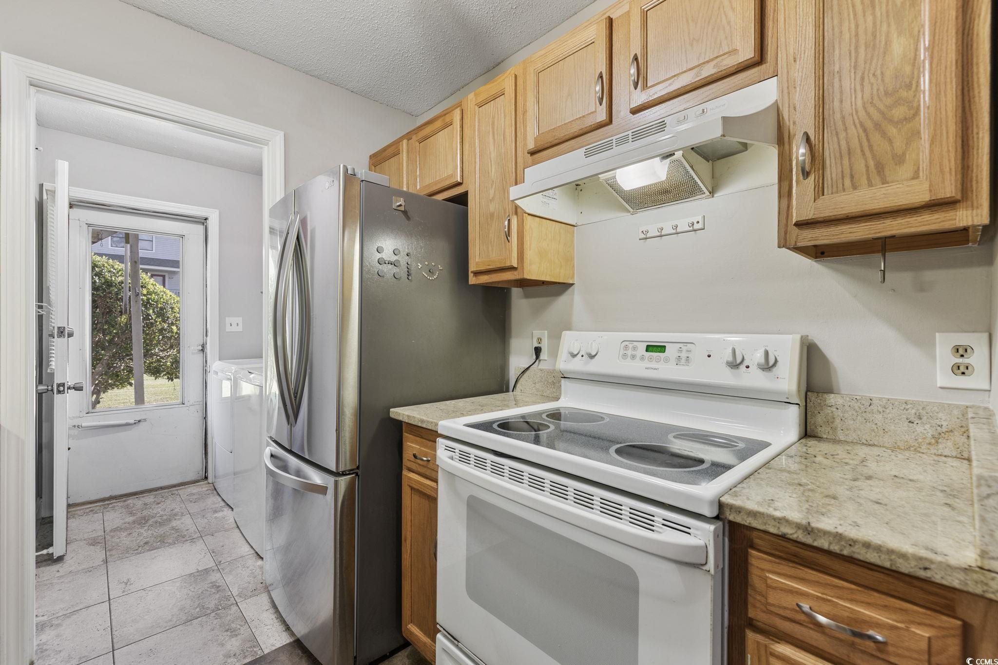 801 Burcale Road, Unit I1 Myrtle Beach, SC 29579 - Photo 10 of 27 Kitchen featuring electric stove, under cabinet range hood, a textured ceiling, separate washer and dryer, and light stone counters