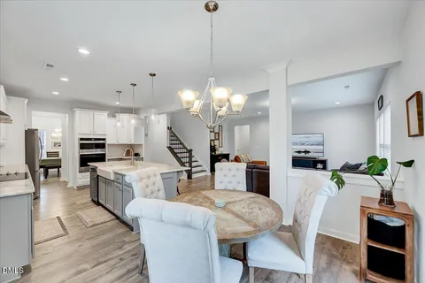 a view of a dining room and livingroom with furniture wooden floor a chandelier