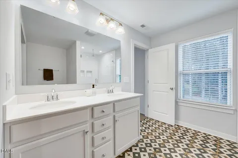a spacious bathroom with a double vanity sink a mirror and a shower