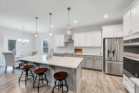 a kitchen with stainless steel appliances granite countertop a sink a stove a refrigerator and island with wooden floor