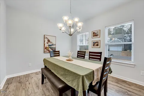 a dining room with wooden floor a chandelier a wooden table and chairs
