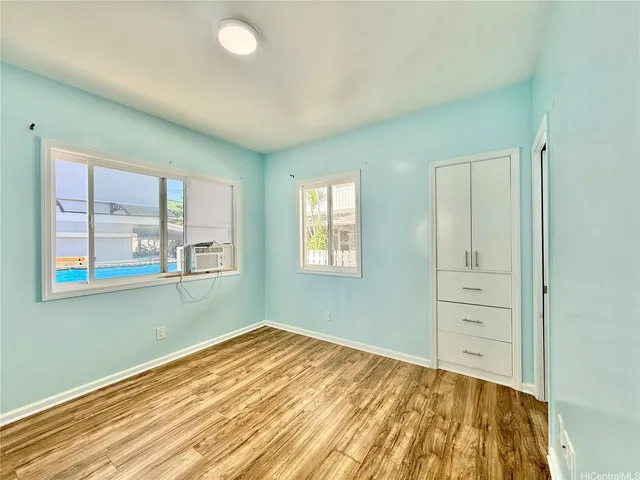 a view of empty room with window and wooden floor
