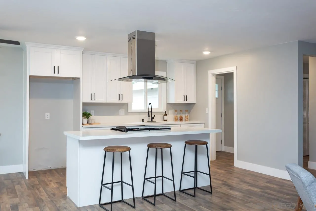 12055 Royal Road El Cajon, CA 92021 - Photo 11 of 34 a kitchen with stainless steel appliances granite countertop a table chairs stove and white cabinets