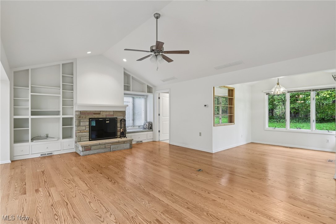 33300 South Woodland Road Cleveland, OH 44124 - Photo 14 of 50 Unfurnished living room with light wood-type flooring, a fireplace, high vaulted ceiling, built in shelves, and ceiling fan