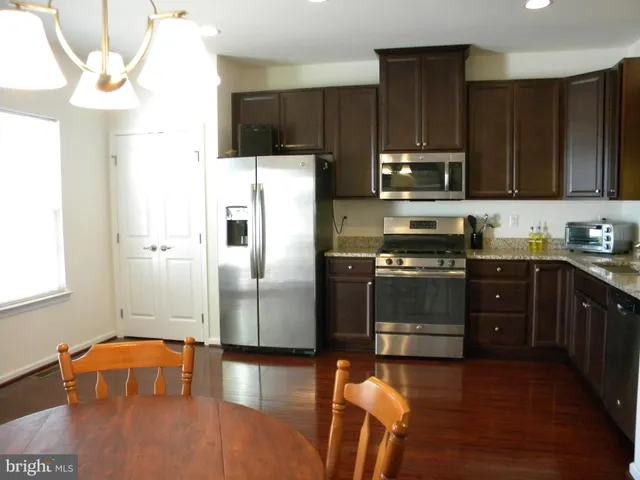 a kitchen with stainless steel appliances a refrigerator a stove a sink cabinets and a wooden floor