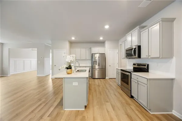 a kitchen with stainless steel appliances granite countertop a stove top oven a refrigerator a sink and dishwasher with wooden floor