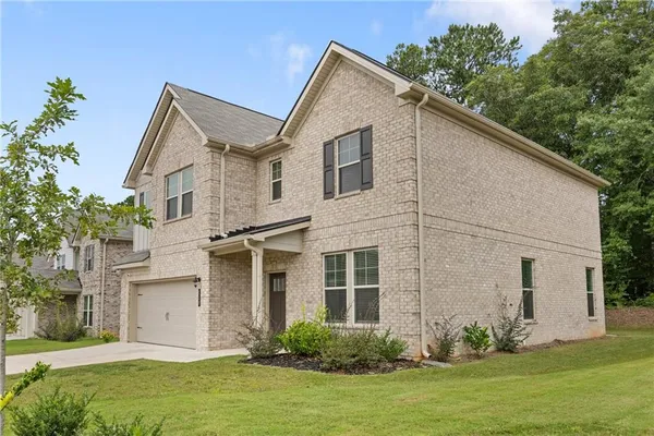 a view of a white house next to a yard with potted plants