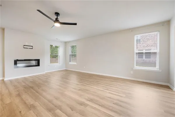a view of an empty room with a window and wooden floor