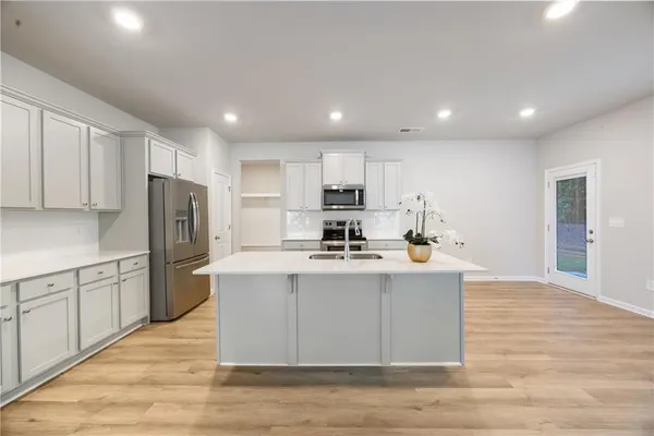 a kitchen with stainless steel appliances granite countertop a sink a stove a refrigerator cabinets and a center island