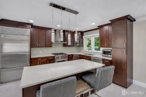 a kitchen with stainless steel appliances a table chairs refrigerator and microwave