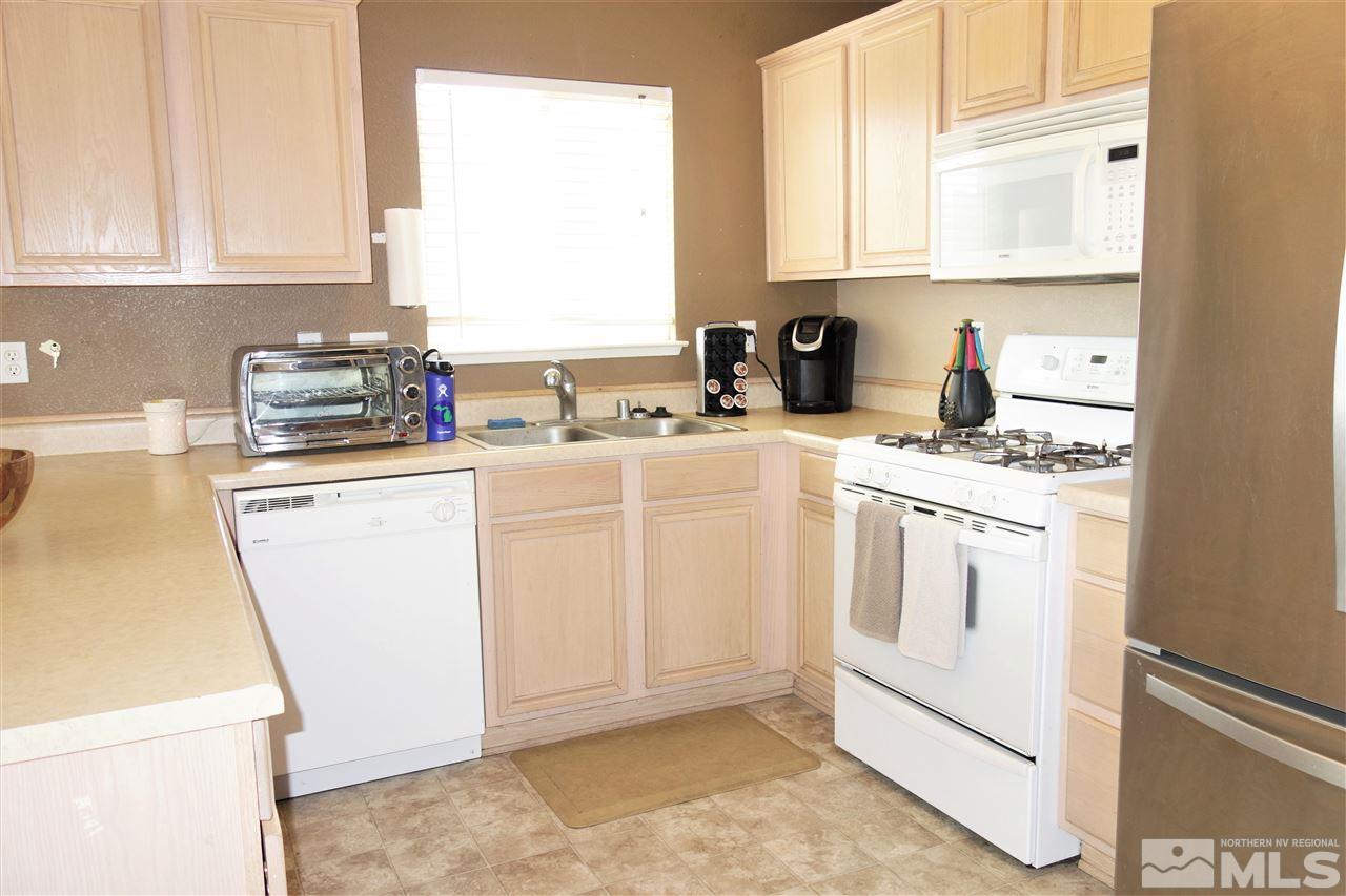 18470 Datewood Court Reno, NV 89508 - Photo 6 of 20 a kitchen with white cabinets sink and white appliances