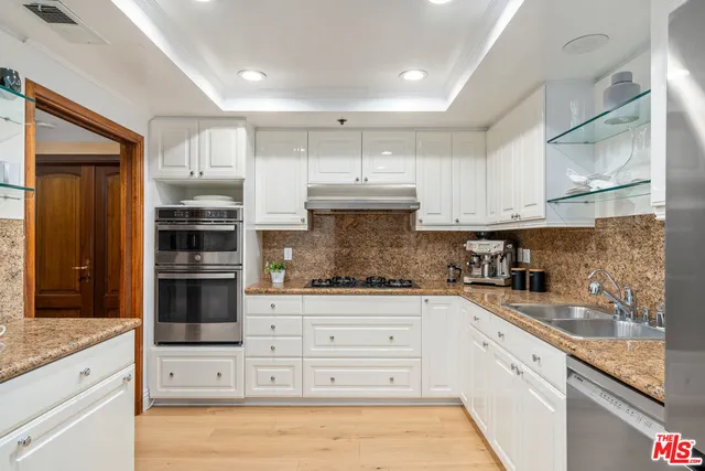 a kitchen with granite countertop white cabinets and stainless steel appliances