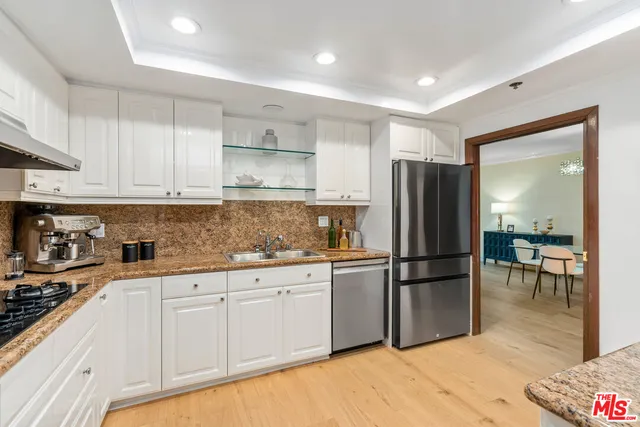 a kitchen with granite countertop a refrigerator and a stove top oven
