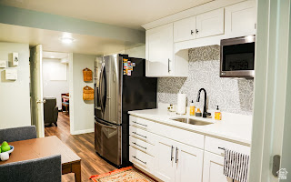 578 High Bench Road Alpine, UT 84004 - Photo 35 of 39 Well-appointed kitchen featuring white cabinetry, light-toned countertops, a patterned tile backsplash, and wood-finish flooring