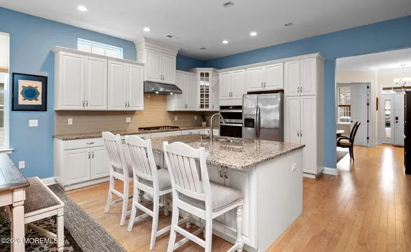 a kitchen with stainless steel appliances granite countertop a stove top oven a refrigerator a sink and a dining table with wooden floor