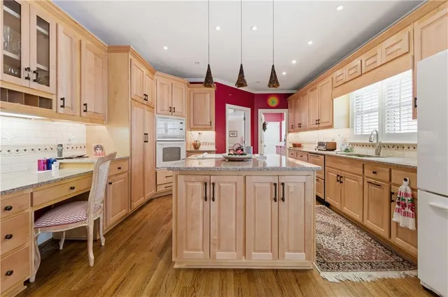 a kitchen with granite countertop a sink appliances cabinets and wooden floor