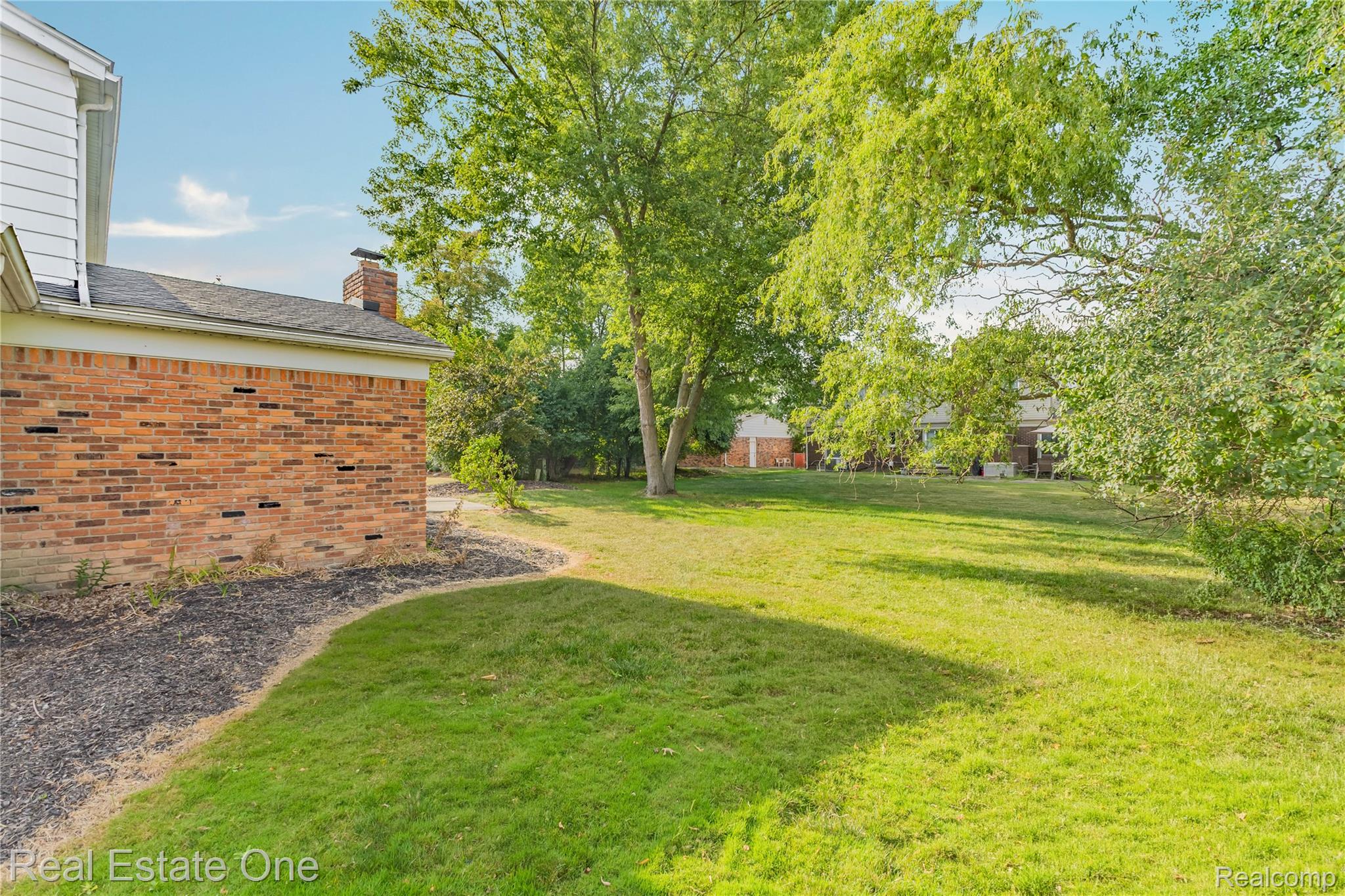 25695 Branchaster Road Farmington, MI 48336 - Photo 51 of 58 Expansive backyard with a manicured lawn, mature trees, and a brick exterior