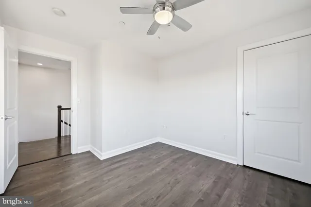 an empty room with wooden floor fan and window