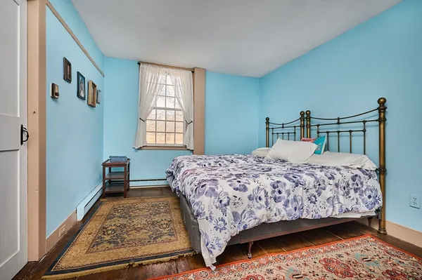 a bedroom with a bed next to a window with a dresser