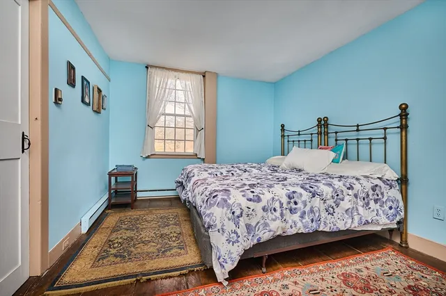 a bedroom with a bed next to a window with a dresser