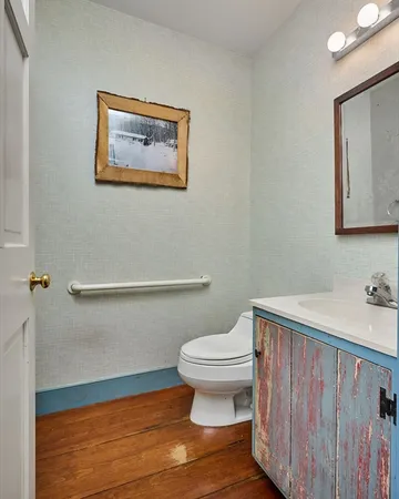 a bathroom with a toilet and a painting on the wall