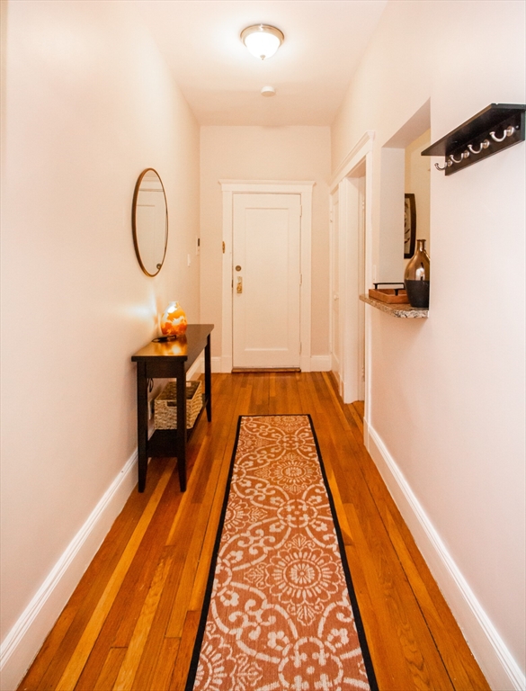 a view of a hallway with wooden floor and a bathroom sink