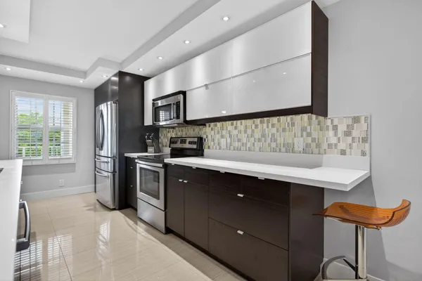 a kitchen with stainless steel appliances kitchen island granite countertop a sink and a refrigerator