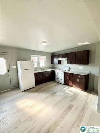 a large white kitchen with stainless steel appliances kitchen island a stove a refrigerator a oven with white cabinets