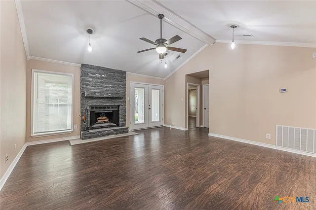 an empty room with wooden floor fireplace and windows