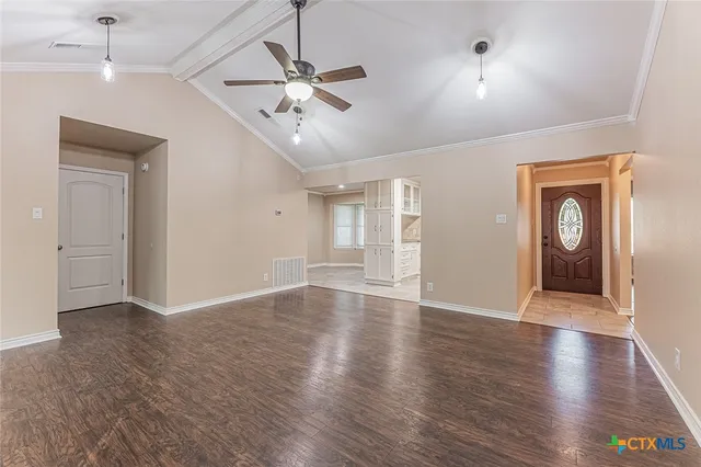 a view of an empty room with wooden floor and a ceiling fan