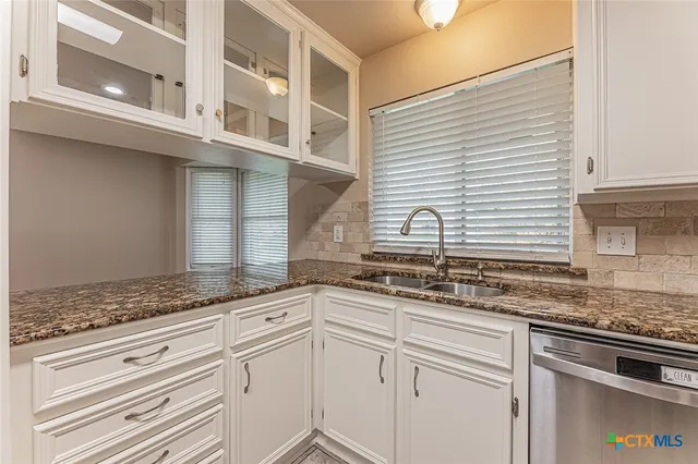 a kitchen with granite countertop stainless steel appliances white cabinets and a sink