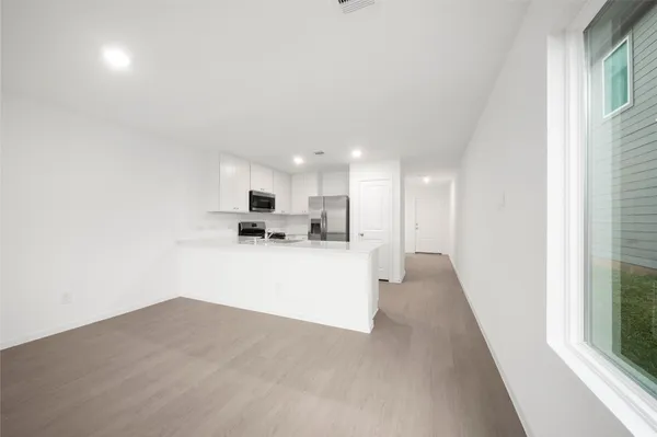 a view of kitchen with kitchen island a sink wooden floor and a refrigerator