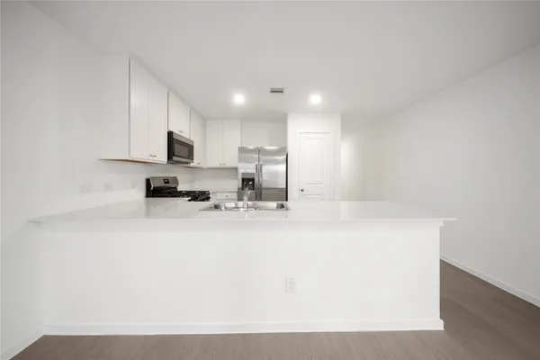 a view of a kitchen with kitchen island a sink wooden floor and a counter top space