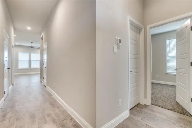 a view of a hallway with wooden floor and a bathroom